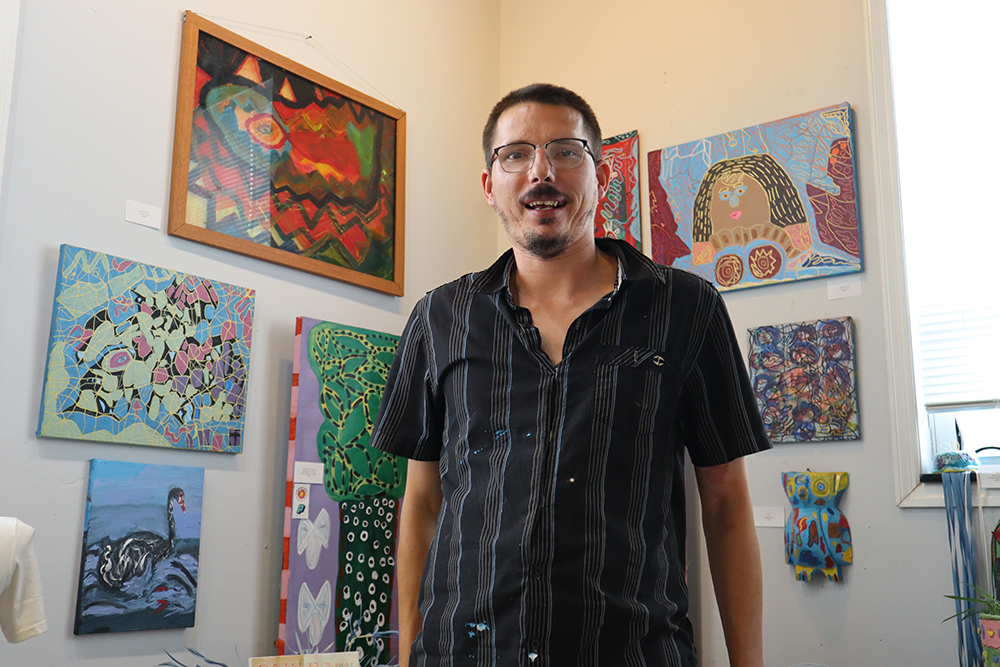 Artist J.J. standing next to his popular “sharpie art,” to his right. Photo by Marilyn Malara.