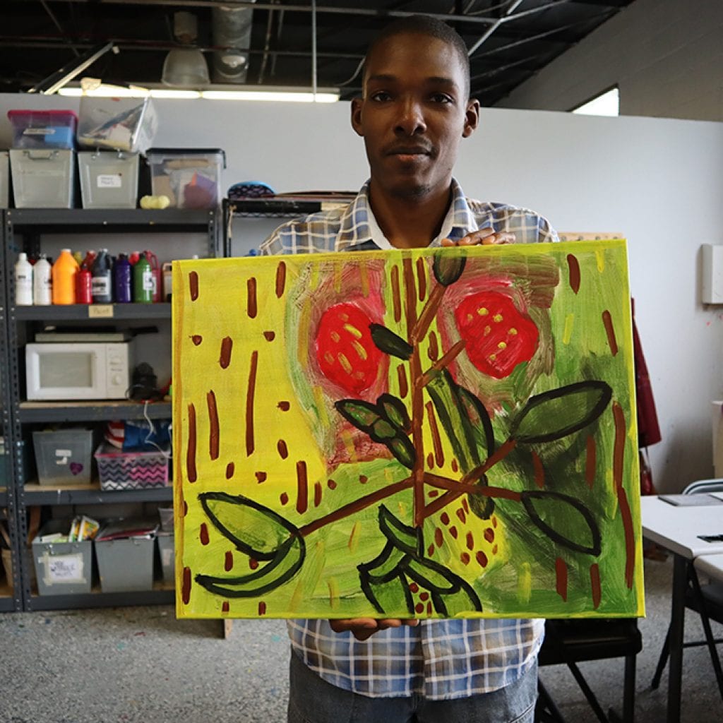 Artist Shawn holding one of his original paintings. Photo by Marilyn Malara.
