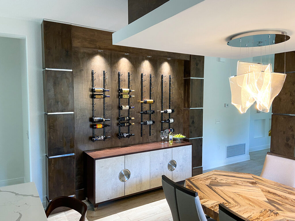The homeowners are wine enthusiasts, so Edwin Ambert created a beautiful wine rack wall with lighting opposite the gorgeous dining table and chairs we selected for them. Photo courtesy of Edwin Ambert Interiors.